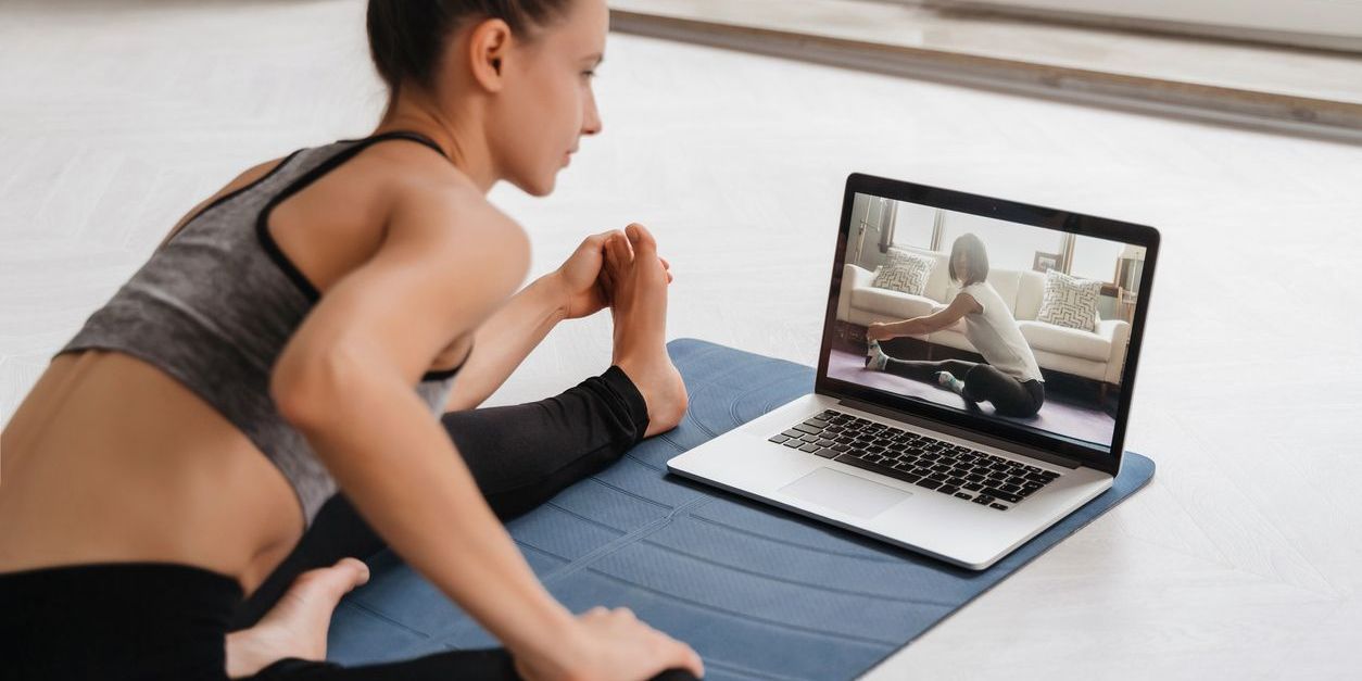 A woman stretching with her online fitness coach.
