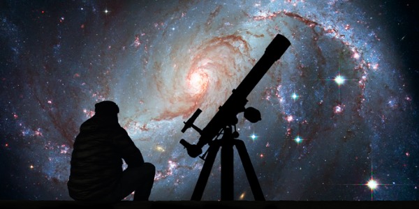 An astronomer sitting outside with a telescope.