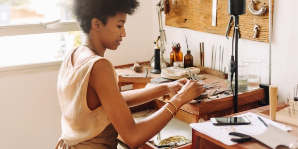 A jeweler designing a piece of jewelry at her workbench.