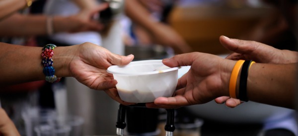 A bowl of food being passed from one hand to another.