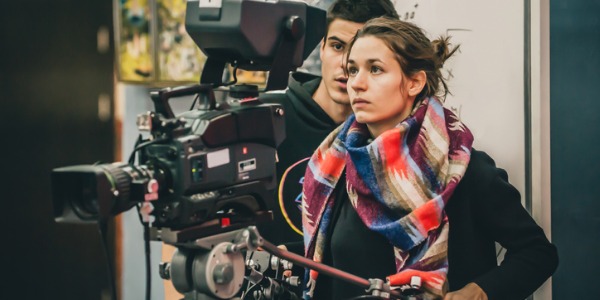 A filmmaker looking through the lens of a camera.